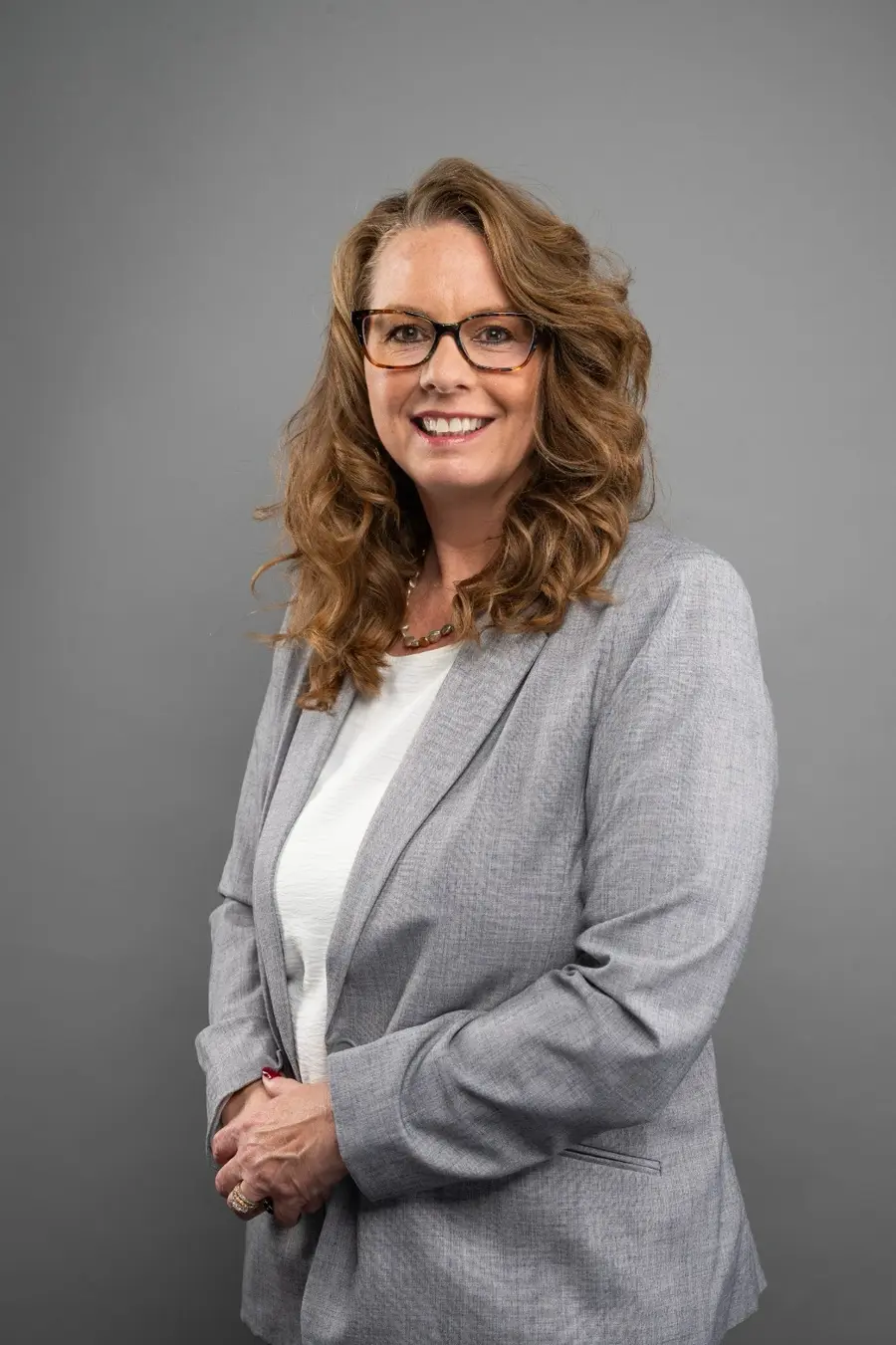 Nellie L. Bushman, smiling, in glasses and a light gray blazer